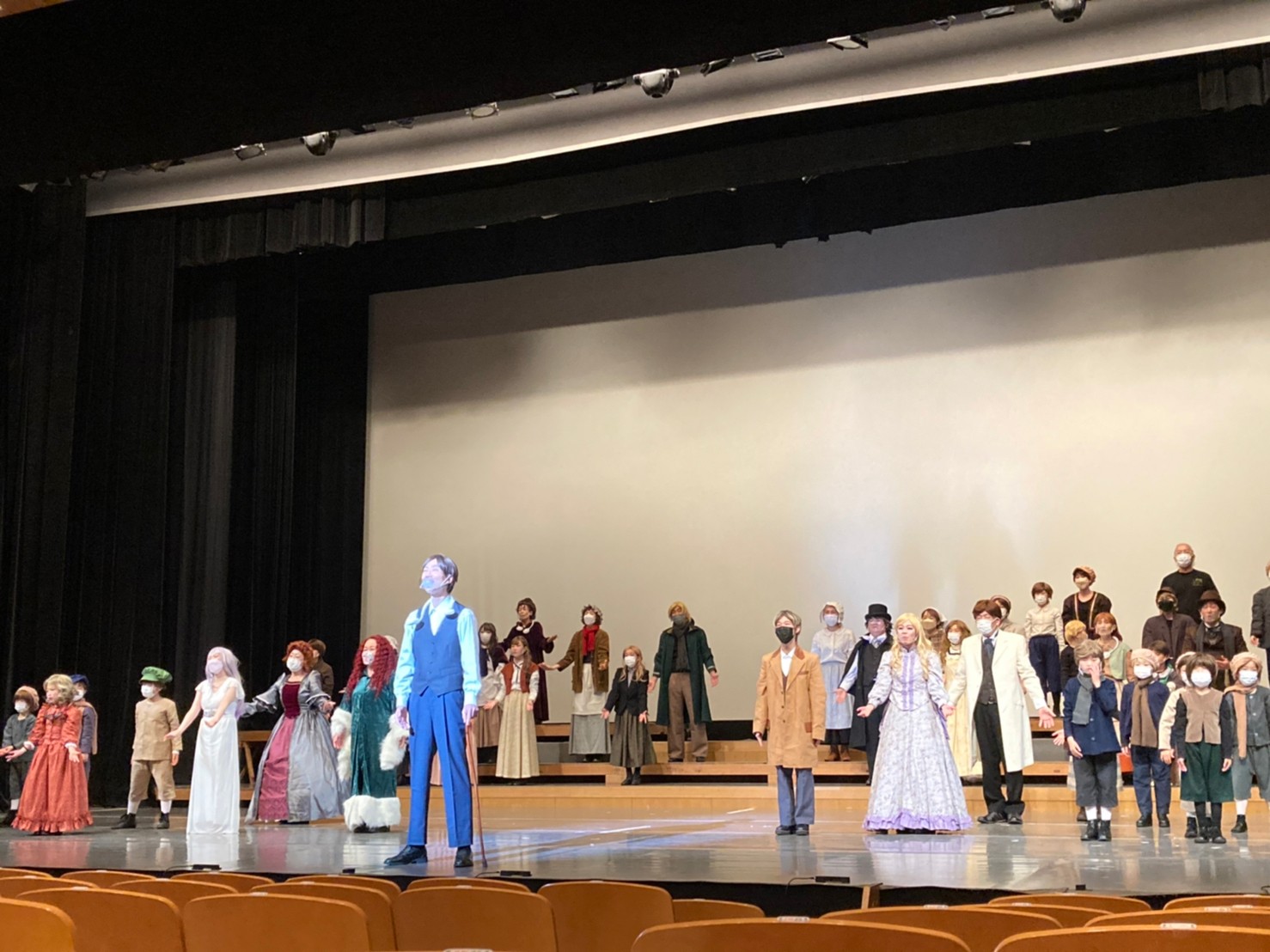 舞台の上で、衣装を着てミュージカルの練習をしている出演者