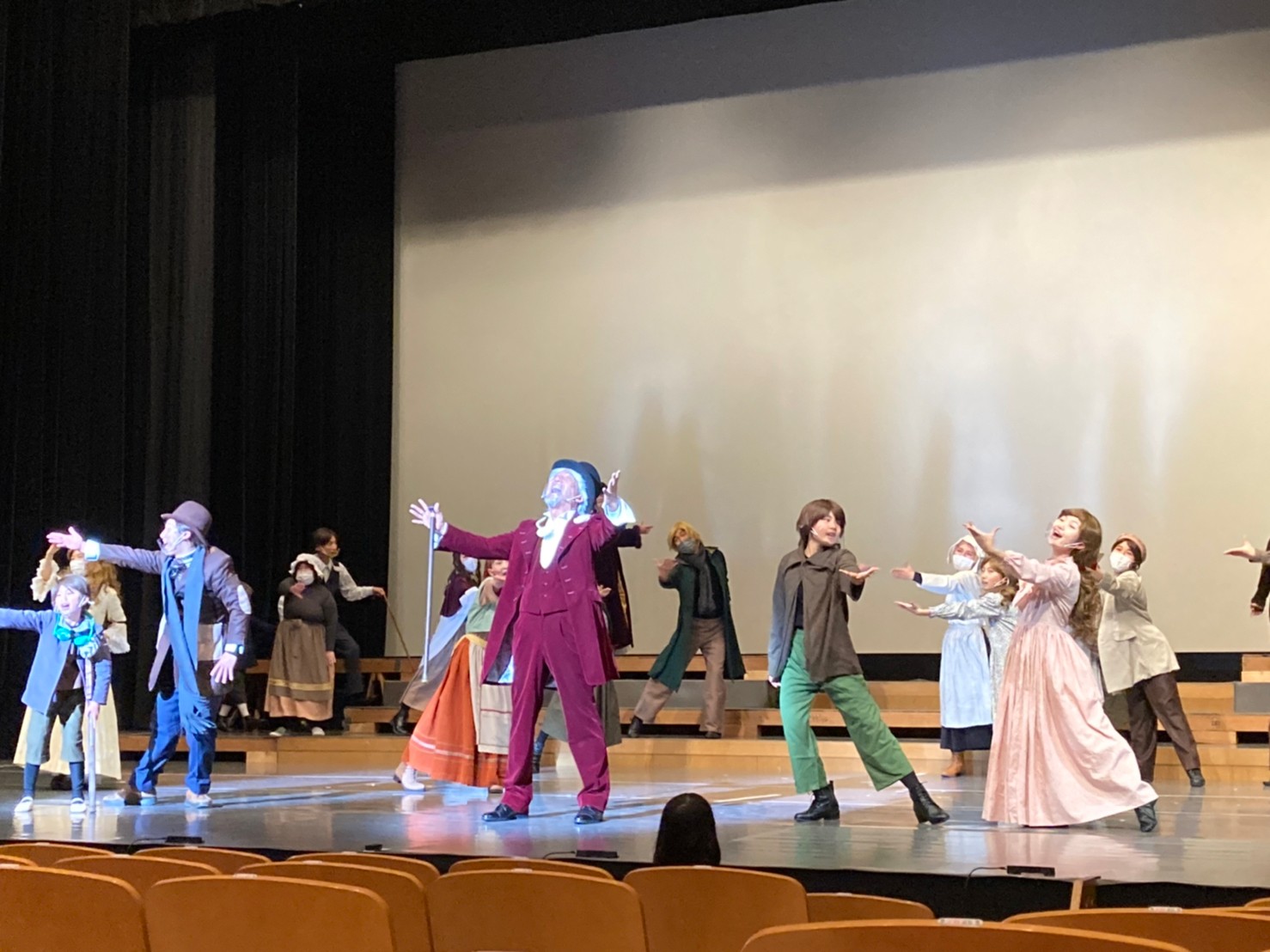 舞台の上で、衣装を着てミュージカルの練習をしている出演者