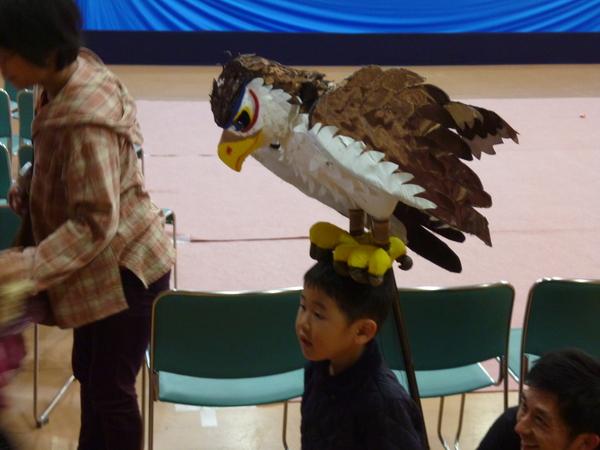 男の子の頭の上に手作りの大きな鷲がのっている写真