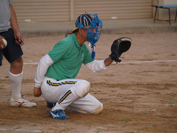 市長が、青いキャッチャーミットを顔につけて、膝をついてかがんでおり、左てに黒いグローブを付けてボールが飛んでくるのを、顔の前で構えている様子の写真