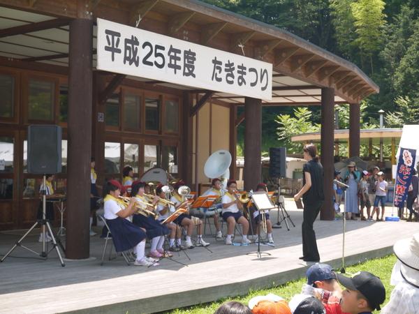 大芋小学校の生徒が赤いベレー帽を被り制服姿で楽器を演奏している写真