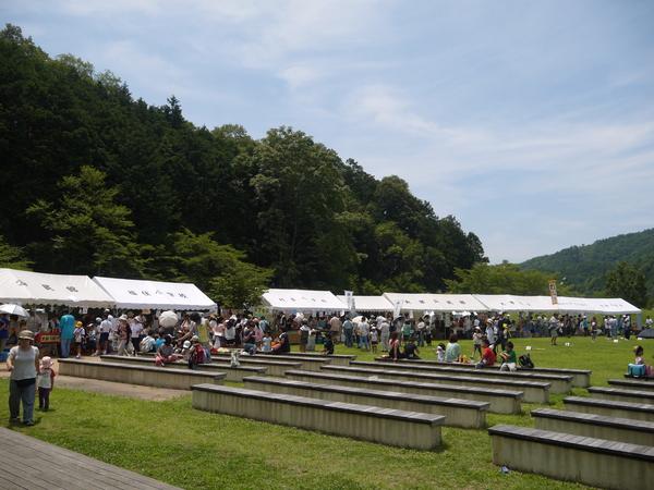 広場ではたくさん白いテントが立てられ、人が集まっている写真