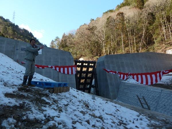 男性がダムを指し、マイクで話をしている写真