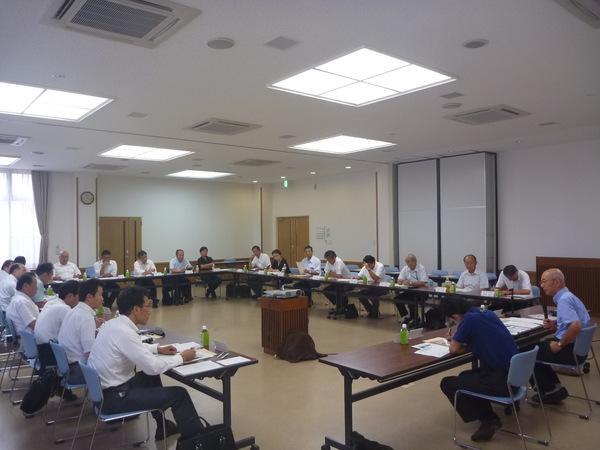 会議室にて、出席者が全員の顔が見えるようにコの字型に座っており、市長の話を真剣に聞いている様子の写真