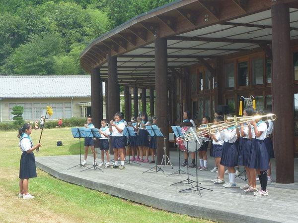 女の子の指揮者を見ながら子供達が演奏している写真