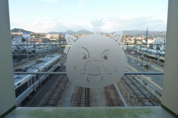 駅のガラスにイメージキャラクターの絵が彫ってあり、外には線路が見えている写真