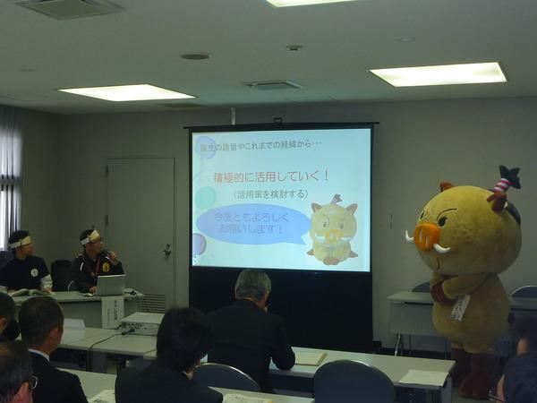 スクリーンに映っているキャラクターが実際に横にいて、男性が話をしている写真