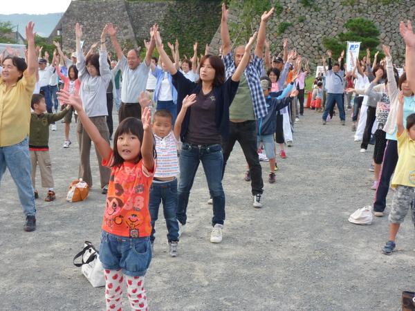 両手を上にあげている子供や、大人たちの写真