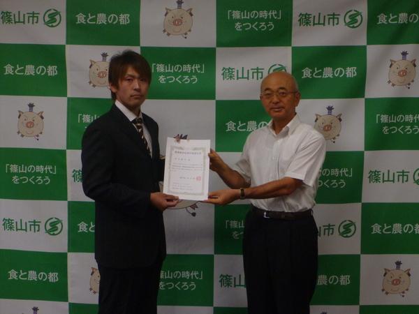清水 健司さんと酒井市長が2人で農業経営改善計画認定書をもって記念撮影している写真