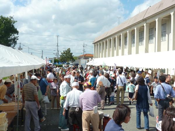 両脇に販売店のテントが張られ、真ん中の通路に多くの人が歩いている写真