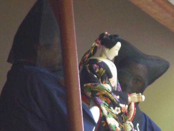 黒子さん2名が、人形を持っている写真