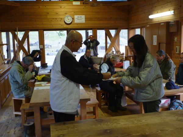 木材でつくられている室内で、市長がグレーのジャンパーを着た女性に終了証を渡している様子の写真