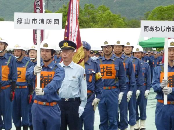 兵庫県消防操法大会の参加者と、篠山市消防団のプラカードを先頭に団員が並んでいる写真