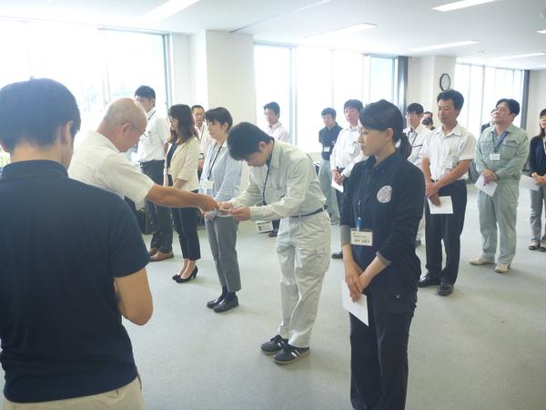 作業着を着た男性が市長から辞令交付を受け取る写真