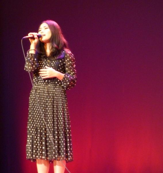 水玉模様のワンピースを着た遠山 恵さんがマイクを持ち歌っている写真