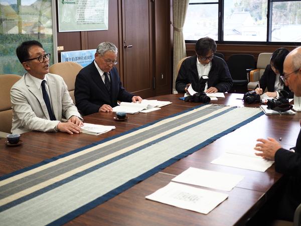 丹後委員長が話をされていて、市長と他の方が資料を見ている写真