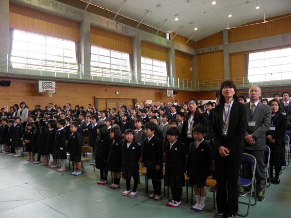 体育館の中に低学年の児童が一番前列に並び、後方まで児童及び出席者が整列して並んでいる様子の写真