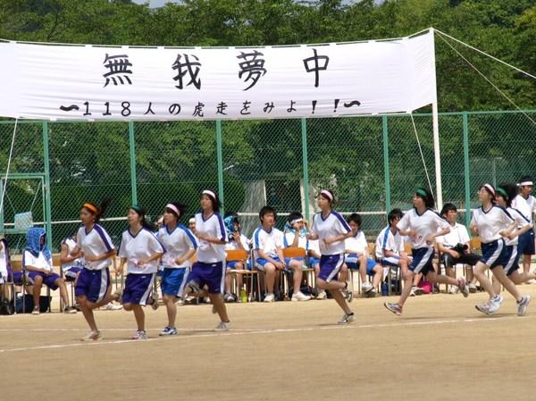 3種類の色の鉢巻きを頭に巻いた女子生徒7名が走りを競っている写真