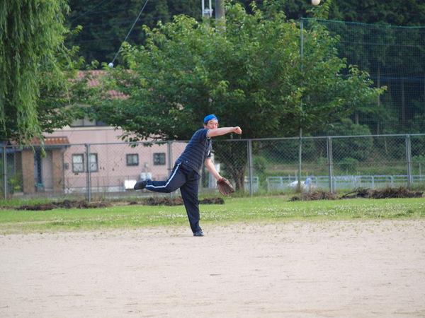 青い帽子のつばを後ろにかぶり、紺色でストラップのポロシャツに紺色のジャージを履いている副市長が、左手にグローブを付けて右手でボールを投げた後の写真