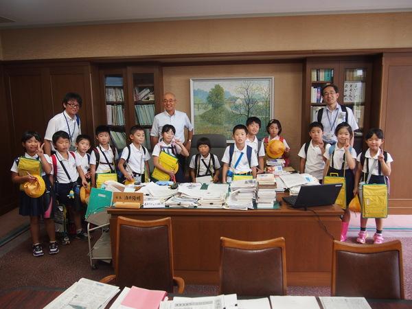 市長室でピースサインを作り笑顔で記念撮影をしている13名の小学生、引率の先生2名と市長の写真