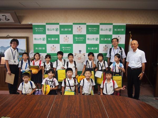 篠山市の横断幕をバックに古市小学校3年生13名と引率の先生2名、市長との記念撮影の写真