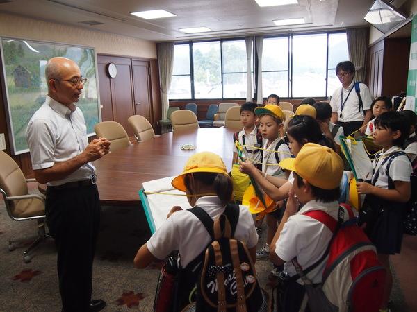 市長の話を真剣に聞きメモを取る生徒たちとそれを見守る引率の先生の写真