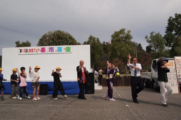 みんなで円になって両手を振り上げ踊っている写真