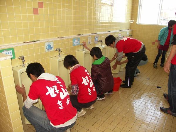 参加者が男子トレイの便器を磨いている様子の写真