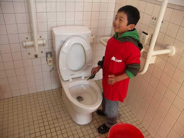 小学生低学年くらいの男の子がトイレ掃除をしている様子の写真