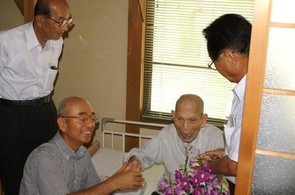 谷後 忠二さんの手を握る手市長と関係者の写真