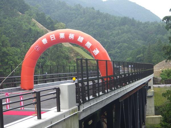 「祝 春日栗柄線開通」のバルーンが道路にかけられている様子の写真