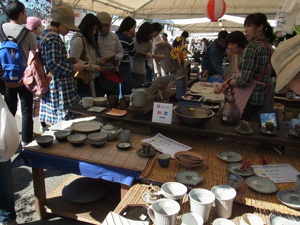 テントの中では色々な形の陶器が販売されて、それをお客さんが買いに来ている写真