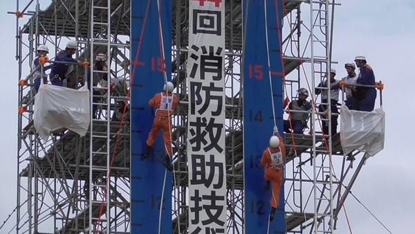 上から吊るされたロープを2名の隊員が登って行って15メートルと目盛りのついた辺りまでそれぞれ上っている写真