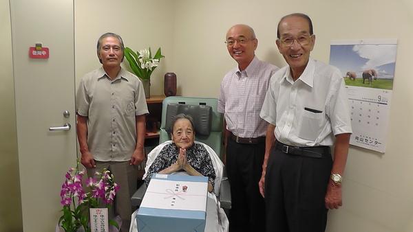 記念品を受け取って嬉しそうな酒井 しず子さんと市長と一緒に記念撮影の写真