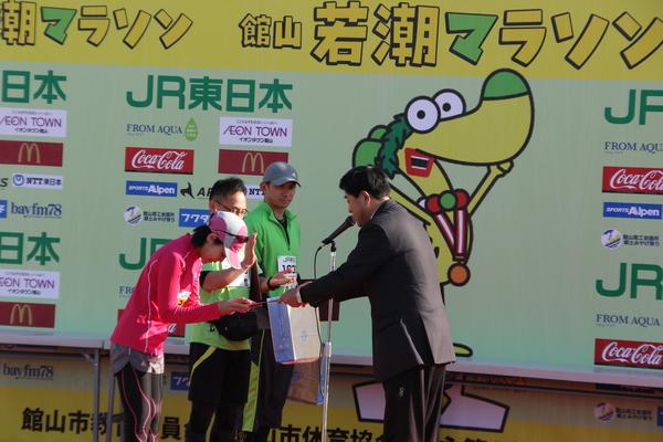 梛野 泰子さんが賞状と記念品を渡されているのを横で見ている小西 隆紀さんと俣野 秀明さんの写真