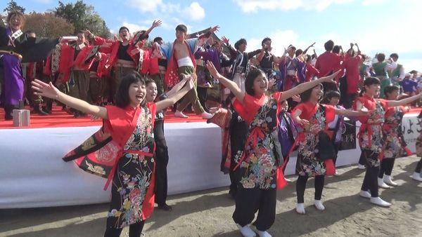 舞台の上と下で子どもから大人まで色々な衣装を着た人たちが、両手を上げて笑いながらポーズをとっている写真