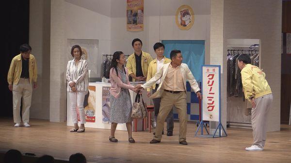 女性が男性の持っているバックを軽く引っ張り男性は引っ張られながらもクリーニングの店員さんとお話している写真