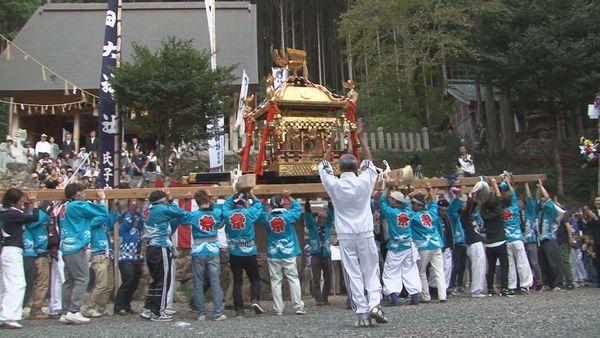 法被を着た地元の方々が金色のお神輿を皆で担いでいる写真