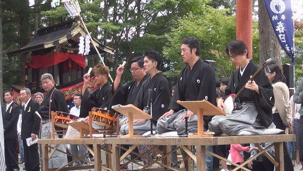 紋付羽織袴を着た男性が締太鼓を叩き三味線を弾きながら演奏している写真
