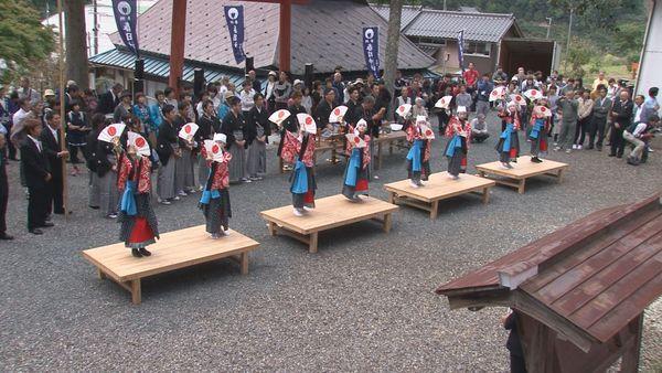 舞台の上で子供達が扇子を持ちみんなで同じポーズをしている写真