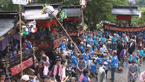 神社に山車が4台停車、その周りで法被を着た地元の方々が賑わっている写真