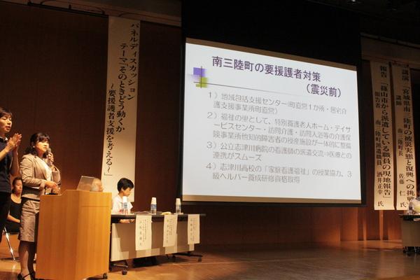 南三陸町の保健師 高橋 晶子さんの南三陸町の要援護者対策(震災前)の映像を使って講演をしている写真