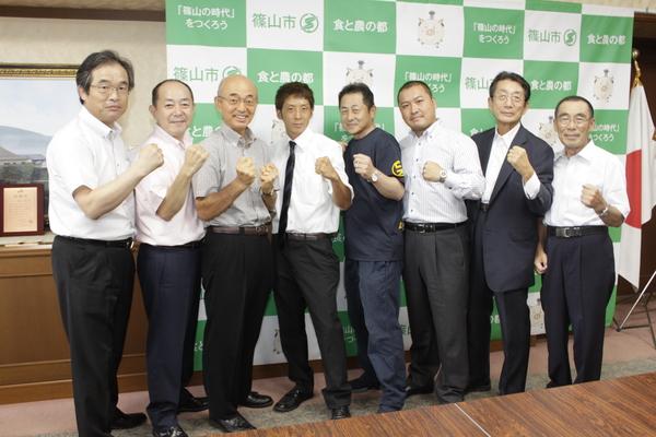 角谷 淳志選手と市長、関係者が、拳を前に整列する集合写真