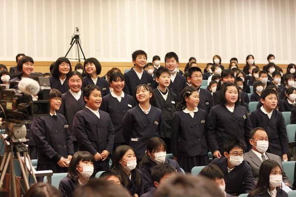 制服を着た小学生が集まっていて、数名が立っている写真