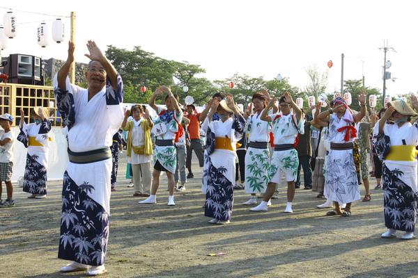 浴衣を着た男性と女性が手を上げて踊っている写真