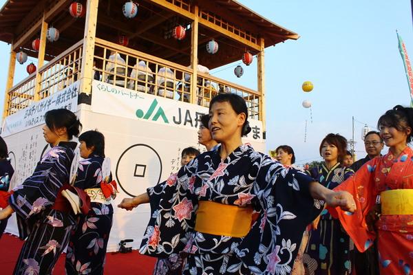 舞台の下で浴衣を着た女性達が手を広げて踊っている写真