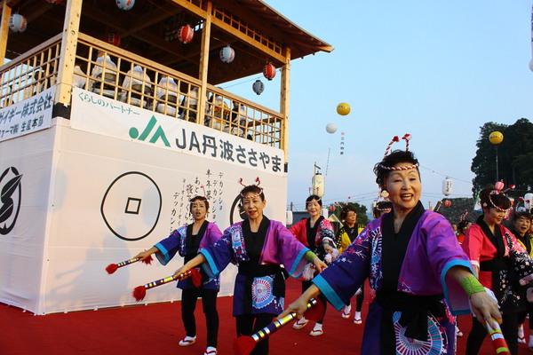 銭太鼓きらり篠山の皆さんがカラフルな衣装を着て舞台の下でバチをもち踊っている写真