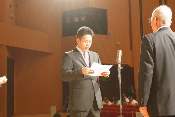新成人代表の男性が舞台に立って宣言の言葉を市長に向かって宣言している写真
