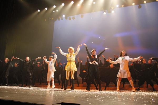 舞台の上で出演者全員で手を広げて楽しそうに歌っている写真