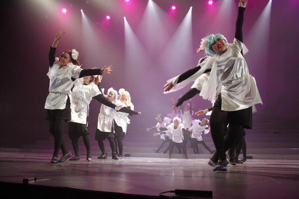 ピンクの照明の中で女性達が笑顔で踊りながら歌っている写真